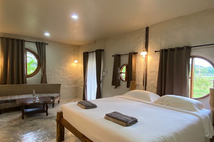 The medium adobe bungalow at Mala Dhara — a double bed under arched windows