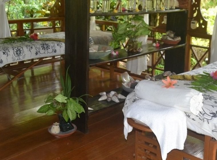 An open-air massage pavilion, tables made up with towels and frangipani